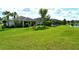 Spacious backyard with playset, green grass, landscaping, and views of a pond and neighboring houses at 11502 Golden Bay Pl, Bradenton, FL 34211