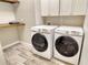 Functional laundry room with modern appliances, wooden shelf and ample cabinet storage for household convenience at 11502 Golden Bay Pl, Bradenton, FL 34211