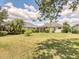 Spacious backyard with lush green grass, mature trees, and a screened-in lanai, perfect for outdoor entertaining at 11714 Forest Park Cir, Bradenton, FL 34211