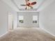 A spacious bedroom with a tray ceiling, a ceiling fan, two windows, and neutral carpet at 11714 Forest Park Cir, Bradenton, FL 34211