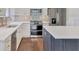 Close-up of a kitchen with white cabinets, quartz counters, stainless steel appliances, and a gray island at 11714 Forest Park Cir, Bradenton, FL 34211