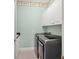 Modern laundry room featuring a washer, dryer, white cabinets, and black and white tiled floor at 11714 Forest Park Cir, Bradenton, FL 34211