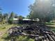 Spacious backyard with mature trees, wood pile and a glimpse of the home in the background at 12127 Hunter Ave, Port Charlotte, FL 33953