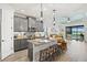 Modern kitchen flows to the living space, featuring granite countertops, gray cabinetry, and an island with bar seating at 13849 Old Creek Ct, Parrish, FL 34219