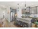 Well-lit kitchen features gray cabinets, stainless appliances, granite countertops, an island with bar seating, and wood floors at 13849 Old Creek Ct, Parrish, FL 34219