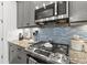 Close-up shot of a stainless gas range, microwave, and patterned backsplash in the kitchen with gray cabinets and granite counters at 13849 Old Creek Ct, Parrish, FL 34219