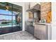 Outdoor kitchen featuring stainless steel grill, stone accent wall, and a pool view at 13849 Old Creek Ct, Parrish, FL 34219