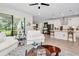 Open-concept living room with white sofas, wood-look floors, and a view into the kitchen, ideal for gatherings at 14787 Gallop Run Dr, Lithia, FL 33547