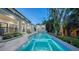 The serene backyard features a pool, spa, lush landscaping, and a modern home with a covered patio at 1607 Flower Dr, Sarasota, FL 34239
