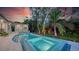 The well-lit backyard features a pool, spa, modern home, and vibrant, tropical landscaping at 1607 Flower Dr, Sarasota, FL 34239