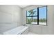 Bright bathroom featuring a modern soaking tub and a large window with a palm tree view at 1607 Flower Dr, Sarasota, FL 34239