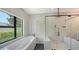 Modern bathroom featuring a soaking tub, walk-in shower, black hardware and a large window at 1607 Flower Dr, Sarasota, FL 34239