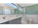 Bright bathroom featuring green accent wall tile, double sinks, and frameless glass shower at 1607 Flower Dr, Sarasota, FL 34239
