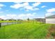 Spacious backyard with a lush green lawn, black fence, pond, and a pergola near the corner of the home at 18317 Gulf Ranch Pl, Bradenton, FL 34211