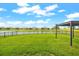 Spacious backyard overlooking the lake, lush green lawn, and black fence at 18317 Gulf Ranch Pl, Bradenton, FL 34211