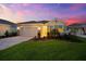 Charming one-story home showcasing a landscaped front yard and brick driveway under a picturesque sky at dusk at 18317 Gulf Ranch Pl, Bradenton, FL 34211