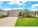Charming one-story home showcasing a landscaped front yard and brick driveway under a bright, partly cloudy, blue sky at 18317 Gulf Ranch Pl, Bradenton, FL 34211