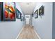 Bright hallway featuring light wood floors, gallery wall, and decorative lighting, leading to the front door at 18317 Gulf Ranch Pl, Bradenton, FL 34211