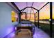 Backyard view of a hot tub with steps, set within a screened-in patio with a lake view at sunset at 18317 Gulf Ranch Pl, Bradenton, FL 34211