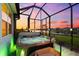 Backyard view of a hot tub with steps, set within a screened-in patio with a lake view at sunset at 18317 Gulf Ranch Pl, Bradenton, FL 34211