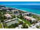 Aerial view showcases tennis courts, lush landscaping, and multiple condo buildings near the beach at 2045 Gulf Of Mexico Dr # M1-505, Longboat Key, FL 34228