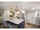 Well-lit kitchen with a center island, woven pendant lighting, and white cabinets at 2045 Gulf Of Mexico Dr # M1-505, Longboat Key, FL 34228