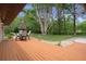Large backyard featuring a wooden deck, green grass, and a mature shade tree at 22063 Lake Lindsey Rd, Brooksville, FL 34601