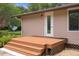 Side view of the home featuring a wooden porch, exterior lighting and lush landscaping at 22063 Lake Lindsey Rd, Brooksville, FL 34601