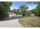 Exterior view featuring a three-car garage adjacent to a spacious driveway and landscaping, showcasing the property's curb appeal at 22063 Lake Lindsey Rd, Brooksville, FL 34601