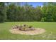 Close-up of outdoor fire pit area featuring a stone-lined fire pit, surrounded by gravel and plenty of room to relax at 22063 Lake Lindsey Rd, Brooksville, FL 34601
