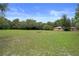 Expansive front yard featuring lush greenery, mature trees, and a charming fire pit, perfect for outdoor gatherings at 22063 Lake Lindsey Rd, Brooksville, FL 34601