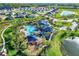 Beautiful aerial view of community pool, clubhouse, and playground with meticulously landscaped grounds and surrounding homes at 2410 Mizner Bay Ave, Bradenton, FL 34208