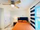 Inviting bedroom features orange bedspread, ceiling fan, and blue-and-white striped curtains at 2410 Mizner Bay Ave, Bradenton, FL 34208