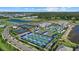Wide aerial view showing the community's tennis and pickleball courts, pool and clubhouse, and community lake at 26000 Seastone Dr, Englewood, FL 34223