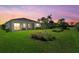 Backyard at sunset featuring lush lawn, screen porch, and tropical foliage at 26000 Seastone Dr, Englewood, FL 34223