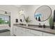 Modern bathroom featuring a double vanity, round mirrors, and easy access to the bedroom at 26000 Seastone Dr, Englewood, FL 34223