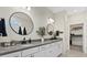 Modern bathroom featuring a double vanity, round mirrors, and a walk-in closet at 26000 Seastone Dr, Englewood, FL 34223