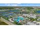 Aerial view of a resort-style community pool, tennis courts, and lush landscaping with a lake backdrop at 26000 Seastone Dr, Englewood, FL 34223