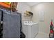 Functional laundry room with washer, dryer, storage rack, and adjacent supplies at 26000 Seastone Dr, Englewood, FL 34223