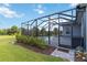 Exterior view showcasing a screened enclosure over brick pavers next to lush yard at 2794 Butterfly Jasmine Trl, Sarasota, FL 34240