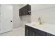 Practical laundry room featuring cabinetry, a sink with gold faucet, and a wire shelf for storage at 2794 Butterfly Jasmine Trl, Sarasota, FL 34240