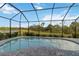 Screened pool with brick paver deck overlooks a lush green backyard and relaxing water view at 2794 Butterfly Jasmine Trl, Sarasota, FL 34240