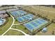 Aerial view of the community's multiple well-maintained tennis courts with shade structures and green surroundings at 2794 Butterfly Jasmine Trl, Sarasota, FL 34240