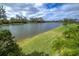 A beautiful view of the lake with green grass and landscaped garden area at 3631 Shimmering Oaks Dr, Parrish, FL 34219