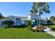 Community clubhouse featuring a blue and white exterior, manicured lawn, and tropical landscaping at 3631 Shimmering Oaks Dr, Parrish, FL 34219