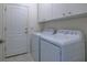 Laundry room equipped with a washer and dryer, white cabinets, and a door at 3631 Shimmering Oaks Dr, Parrish, FL 34219
