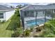 Screened in pool with a grey tiled deck and manicured garden areas with lush green lawn at 3631 Shimmering Oaks Dr, Parrish, FL 34219