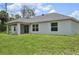A beautiful backyard with a gray house with a covered porch and verdant green grass at 4091 Dull St, North Port, FL 34286
