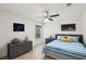 Bright bedroom features a blue and white striped bedspread, grey dresser, and ceiling fan at 4091 Dull St, North Port, FL 34286