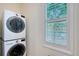 Functional laundry room with a stacked washer and dryer and a window with plantation shutters at 4108 Roberts Point Rd, Sarasota, FL 34242